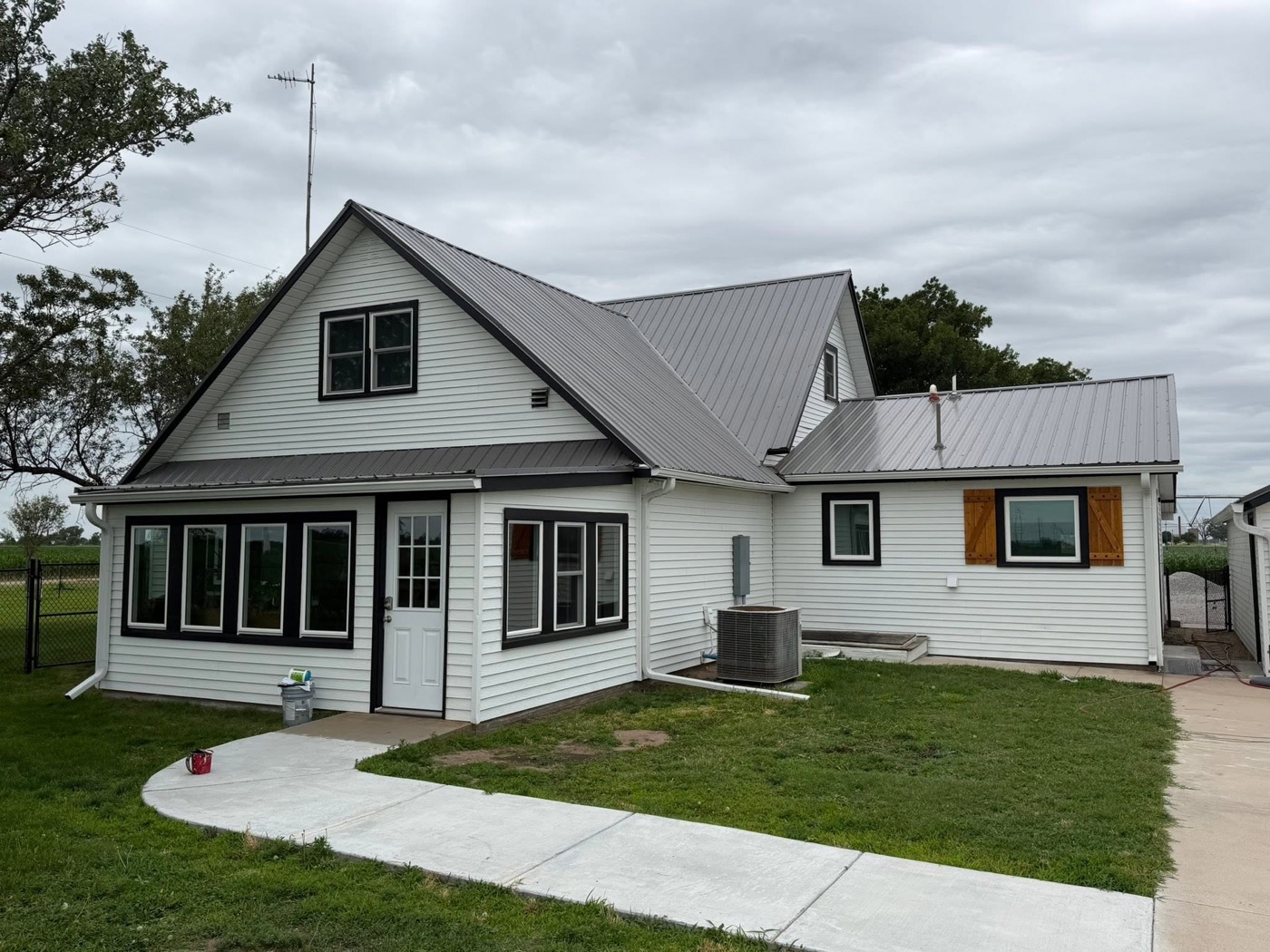 Great Bend farmhouse with fresh white siding and black trim painted by Pure Painting